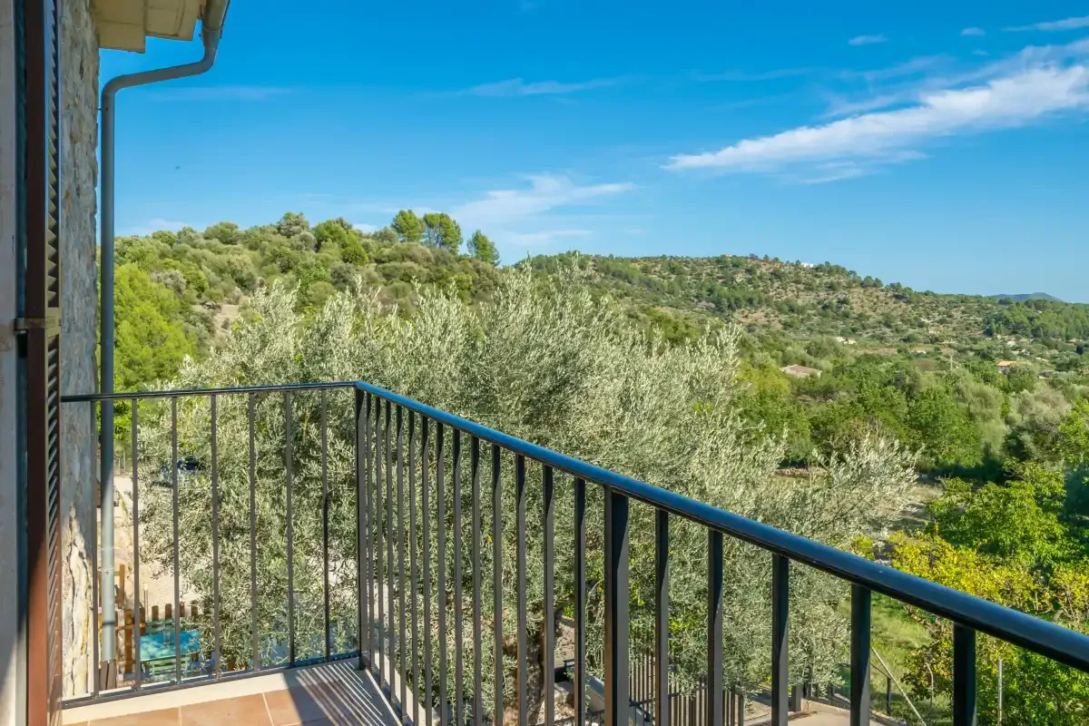 A balcony overlooks a green, tree-covered hillside.