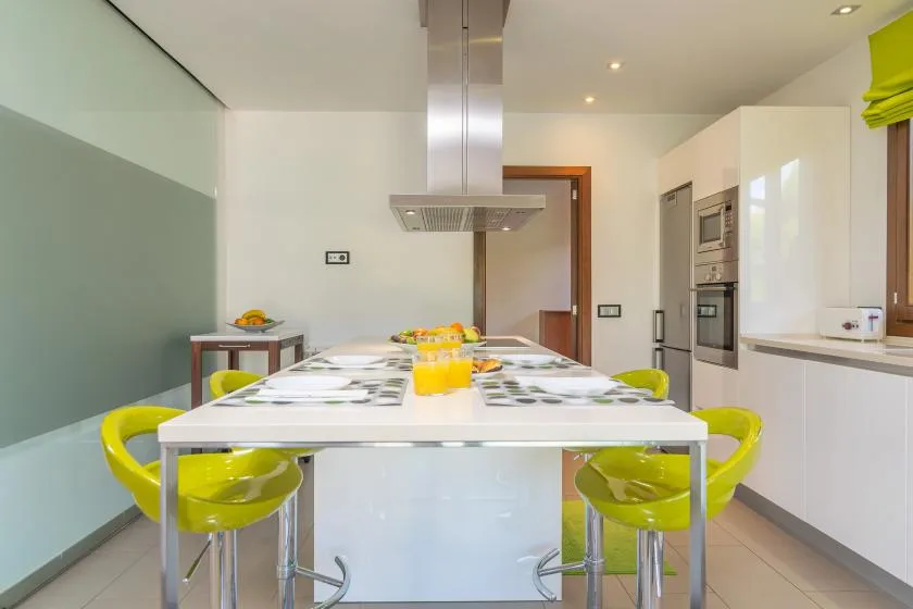 A modern kitchen with a long island and bright yellow seating.