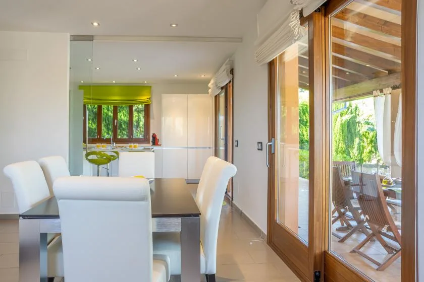 A dining area with white seating beside large glass doors opening onto a patio.