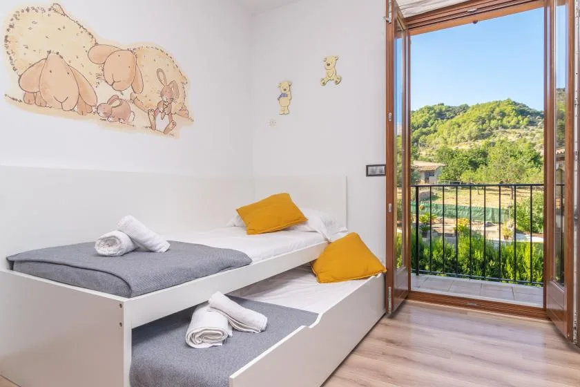 A bright bedroom with two beds beside an open balcony door.