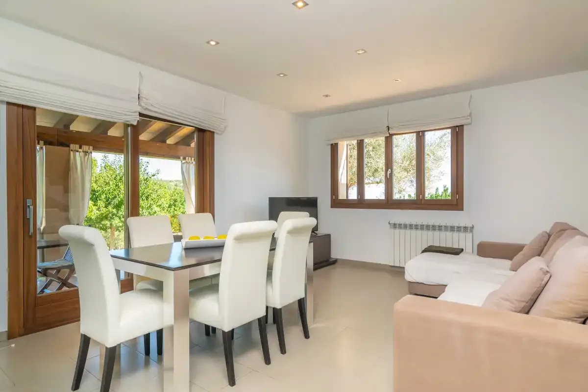 A bright living and dining room with a table, seating, and large windows.
