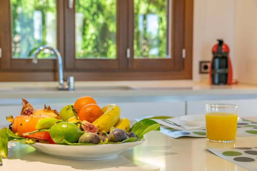 A kitchen counter displays a plate of assorted fruit beside a glass of juice.