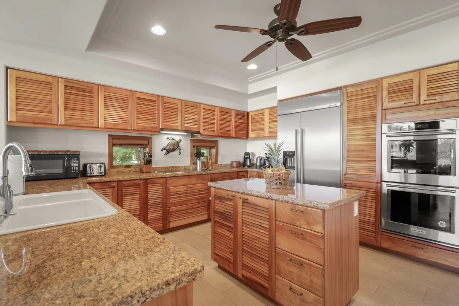 A spacious kitchen with wooden cabinets, stone countertops, and a central island.