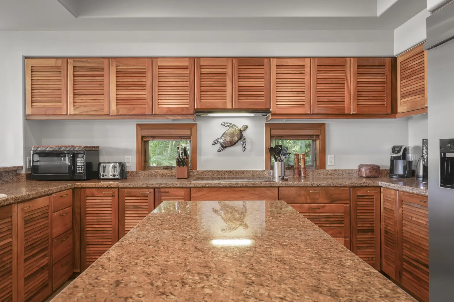 A kitchen with wooden cabinets, stone counters, and a central island.