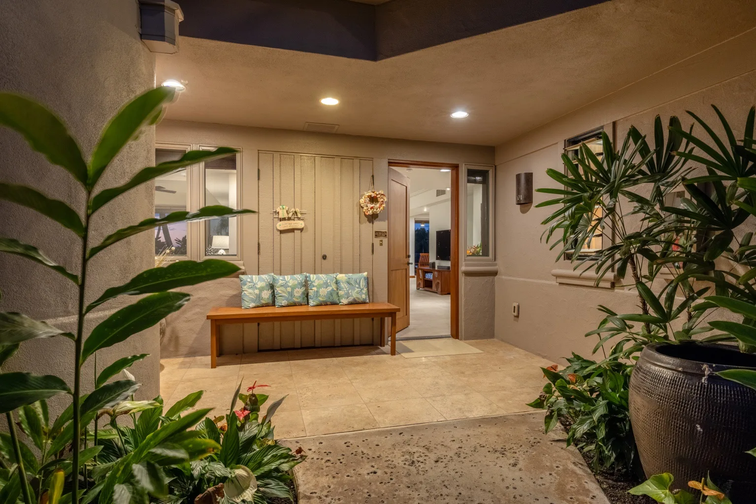 An indoor entry area with a wooden bench and leafy plants.