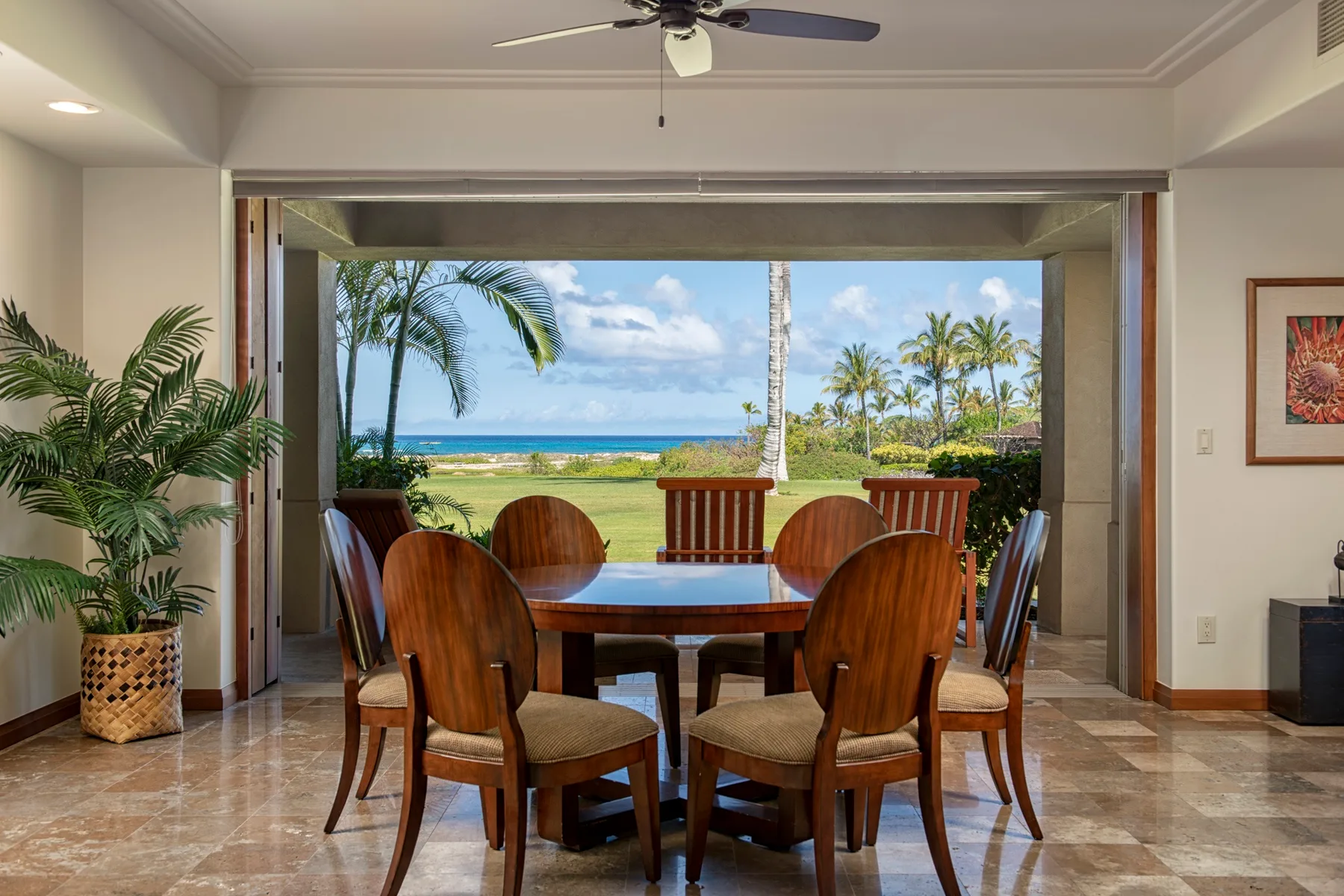 A dining area with a wooden table and chairs faces an ocean view.