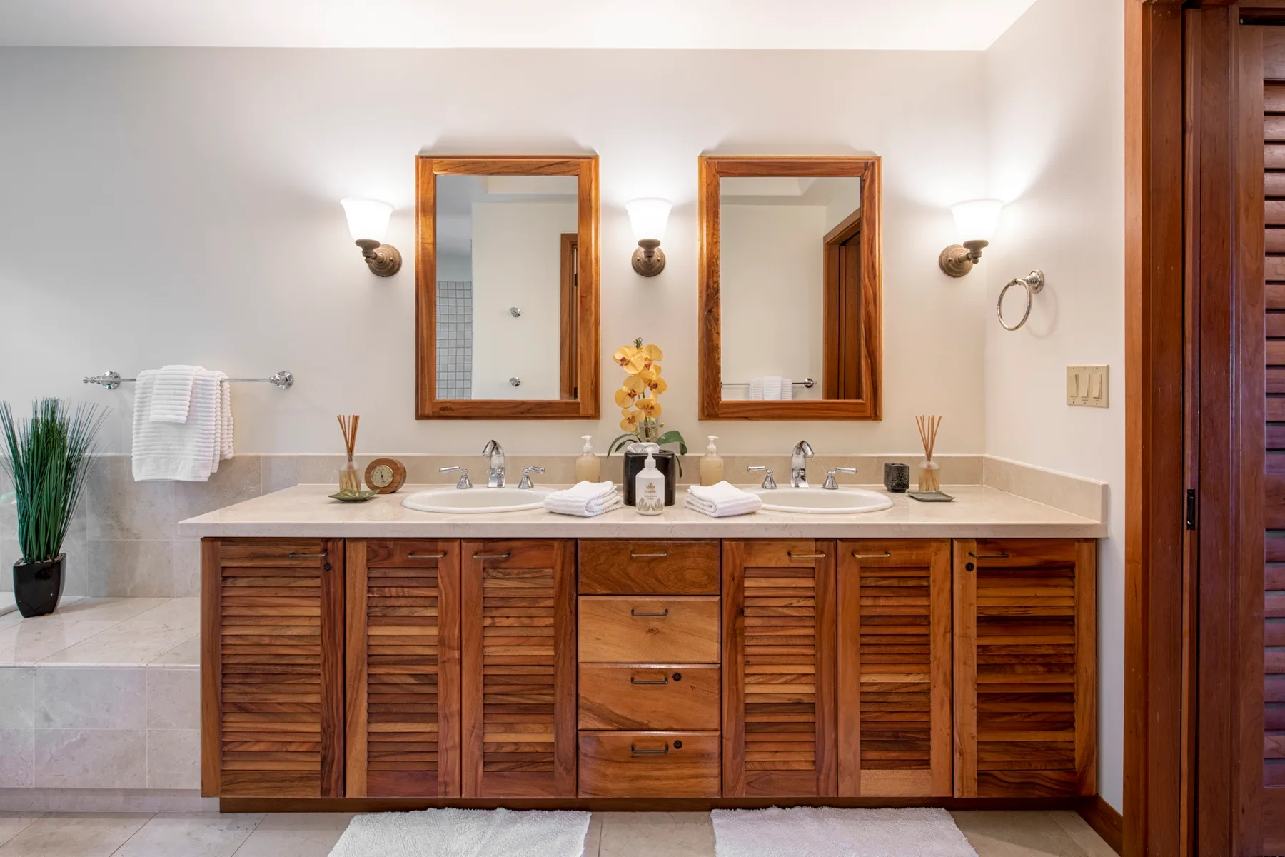 A bathroom vanity with two sinks, wooden cabinetry, and mirrors.