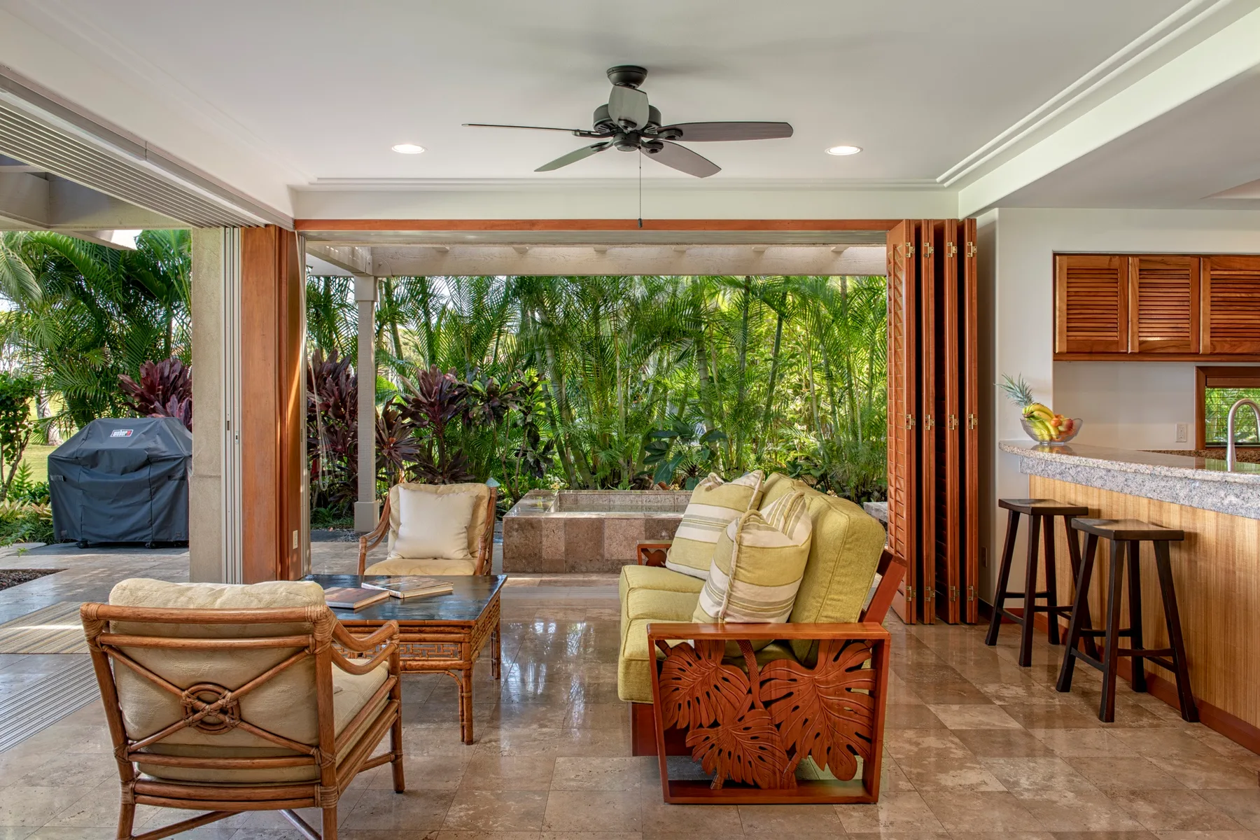 An open-air living area with seating facing a lush garden.
