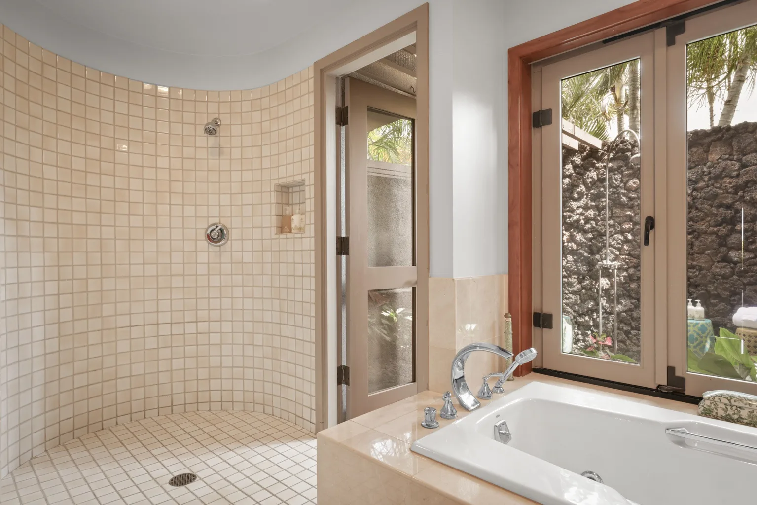 A tiled bathroom with a bathtub beside a window.