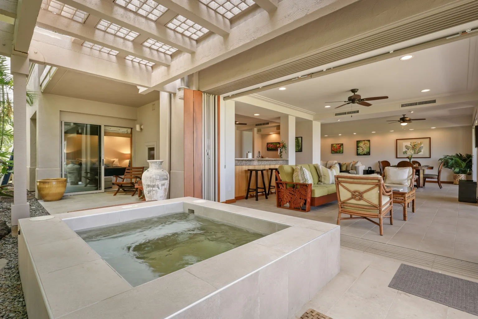 An open-air patio with a built-in soaking tub beside a furnished living area.