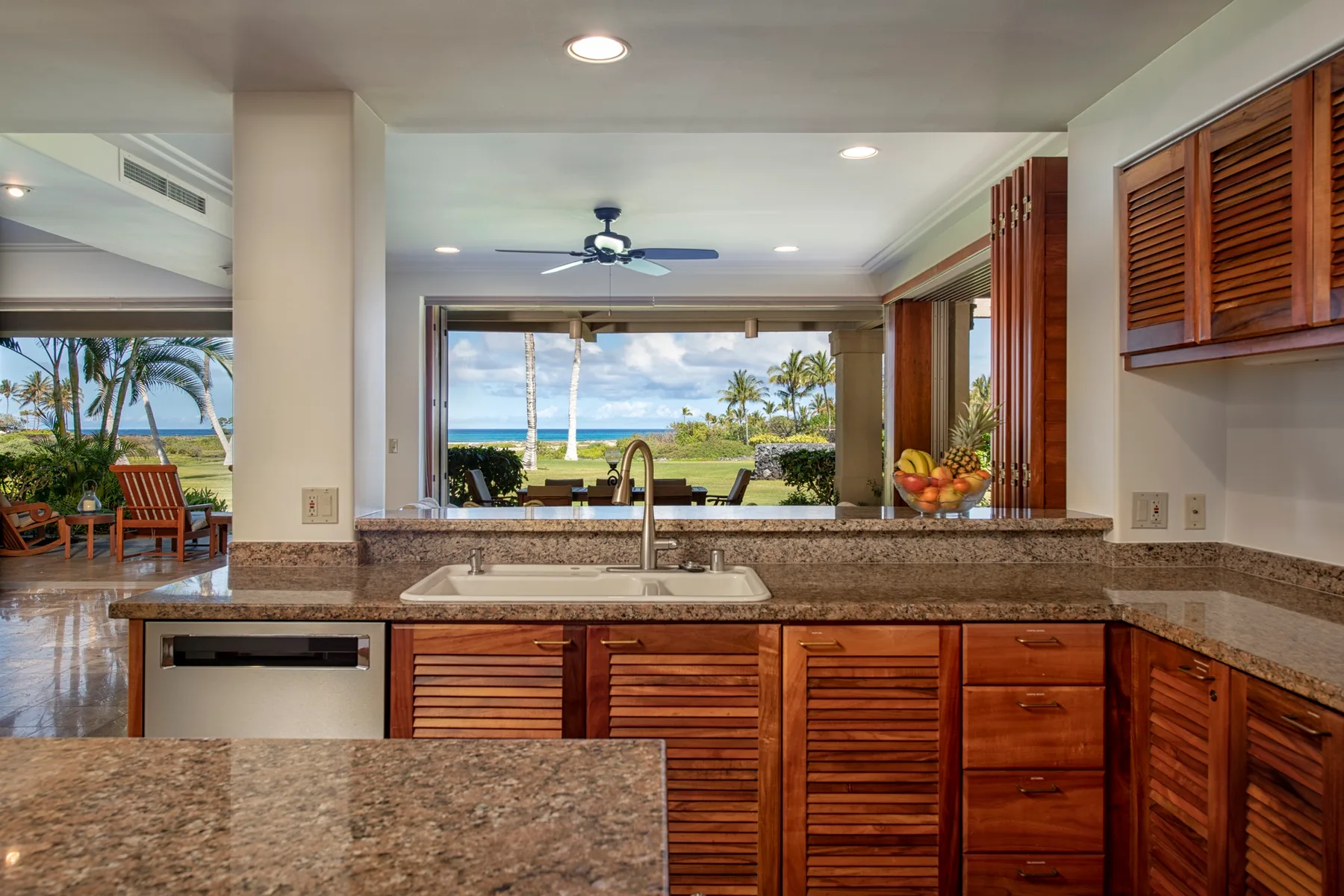 A kitchen with a wide counter overlooks a tropical ocean view.
