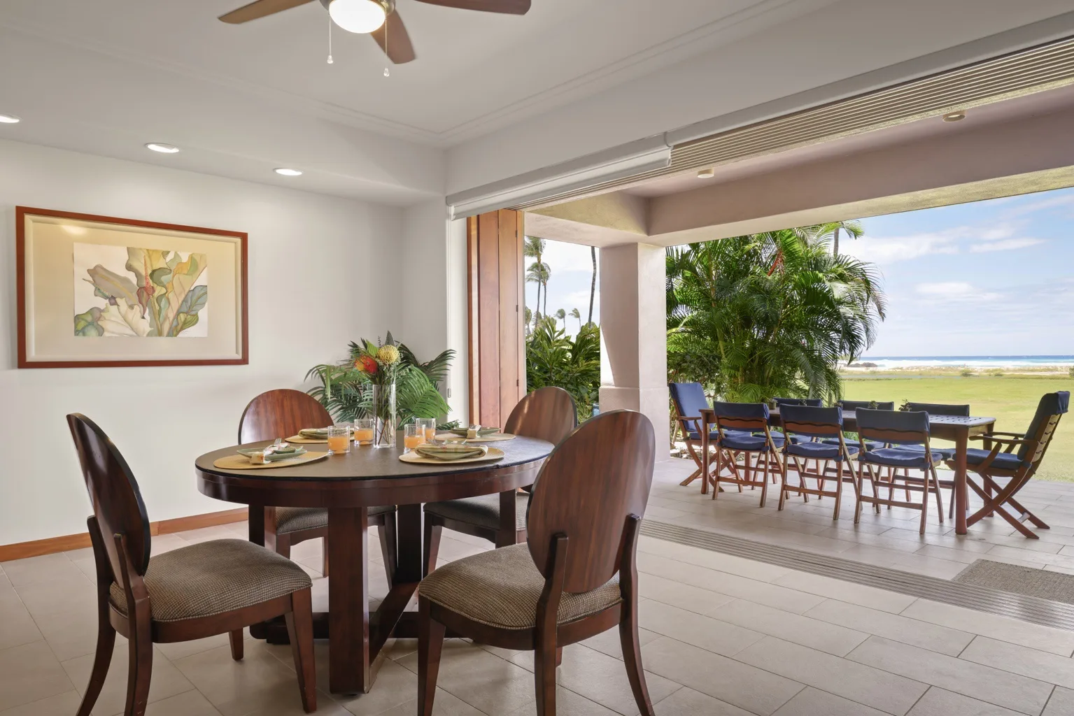 A dining area opens onto a patio with outdoor seating and a beach view.