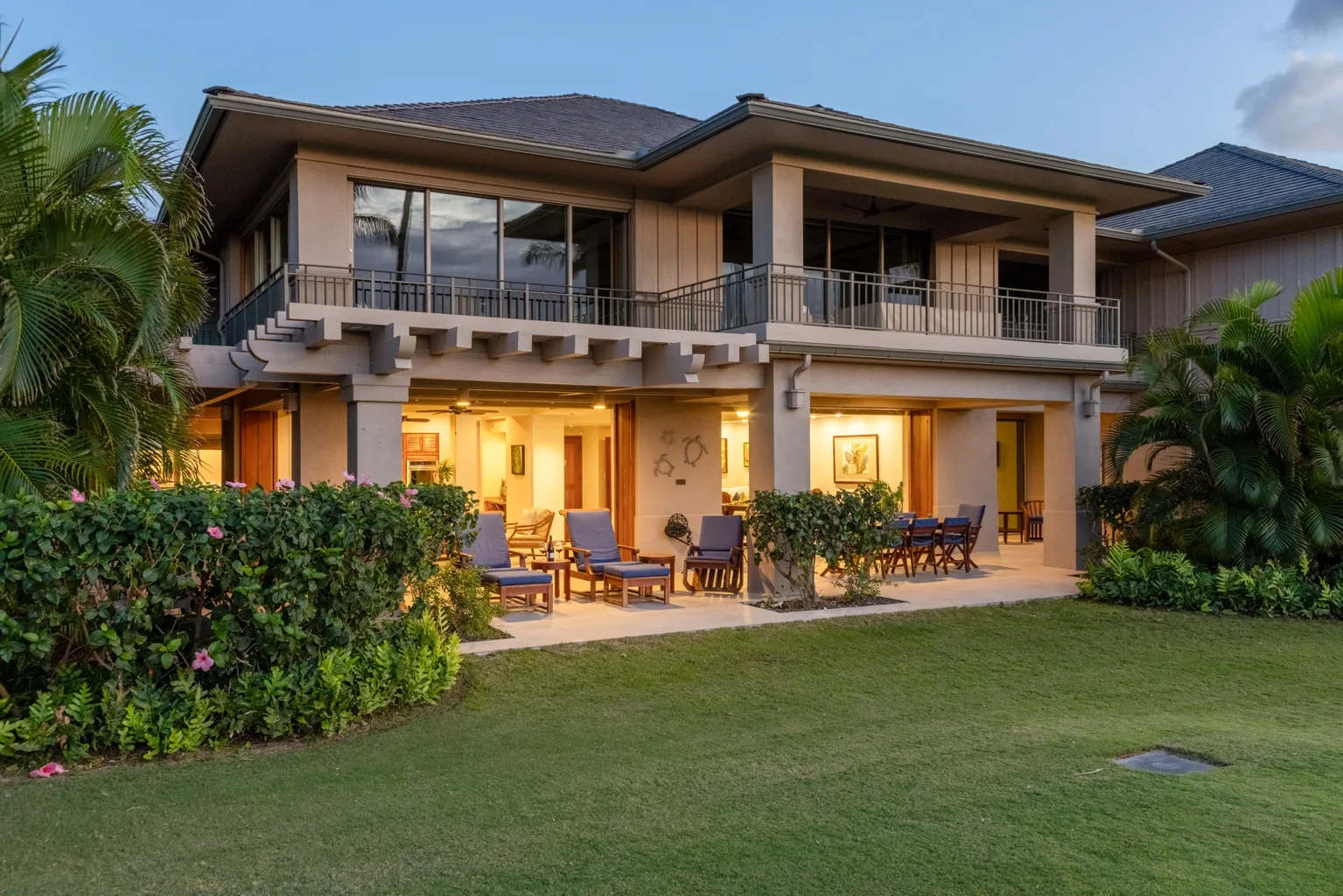 A two-story house with a lawn, garden, and outdoor seating.
