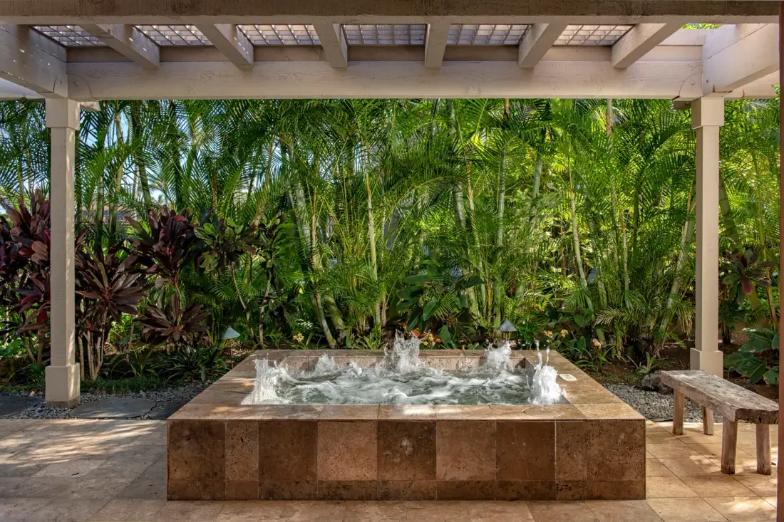 A covered outdoor spa sits amid dense tropical greenery.
