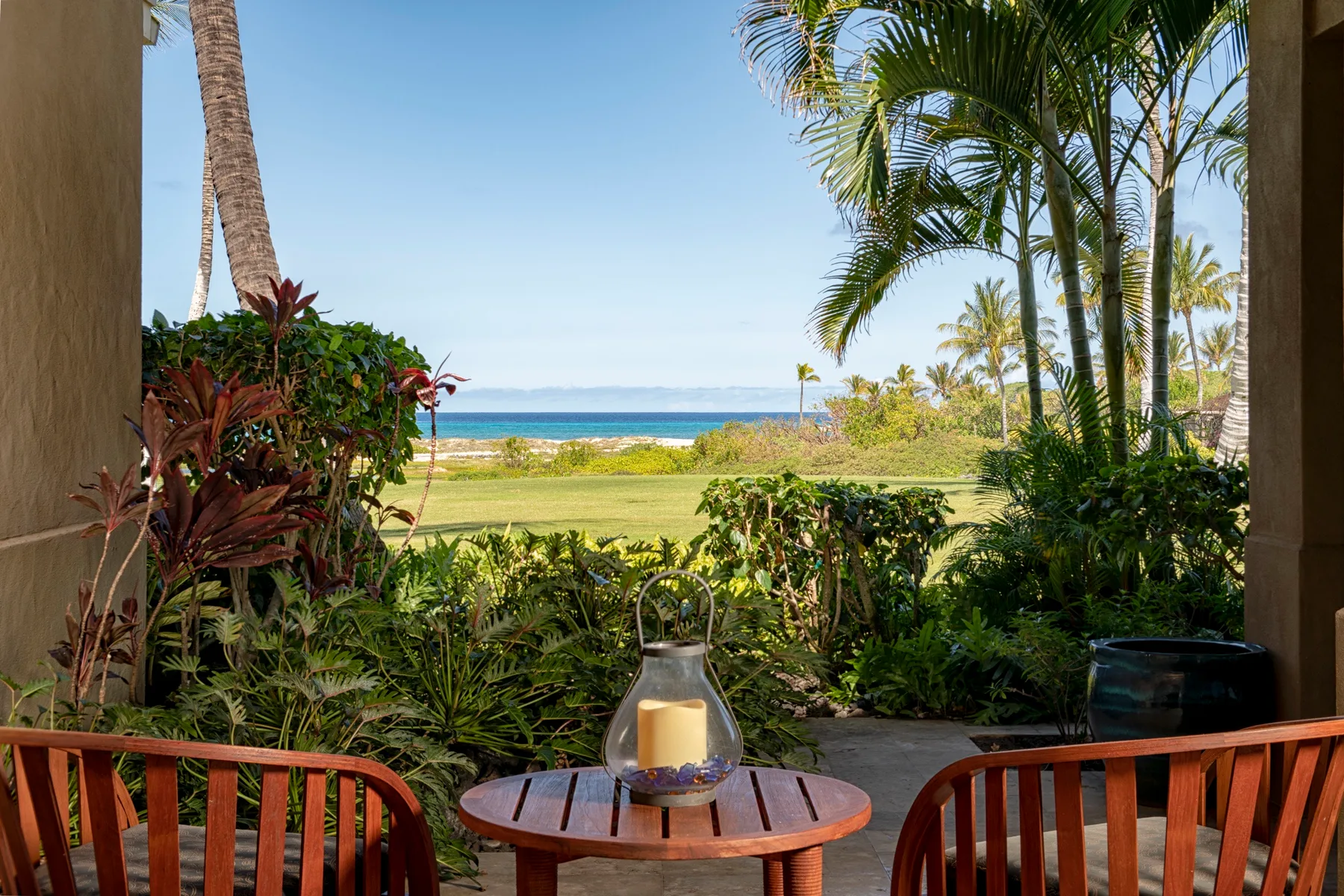 Outdoor patio seating overlooks a landscaped garden and the ocean.