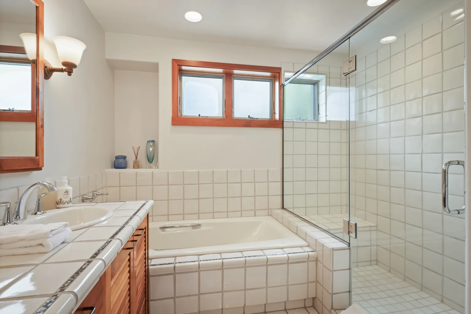 A tiled bathroom with a bathtub, glass shower, and vanity.