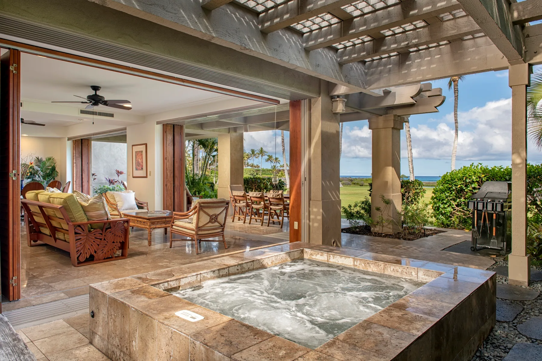 A bubbling hot tub sits beside an open-air lounge overlooking the ocean.