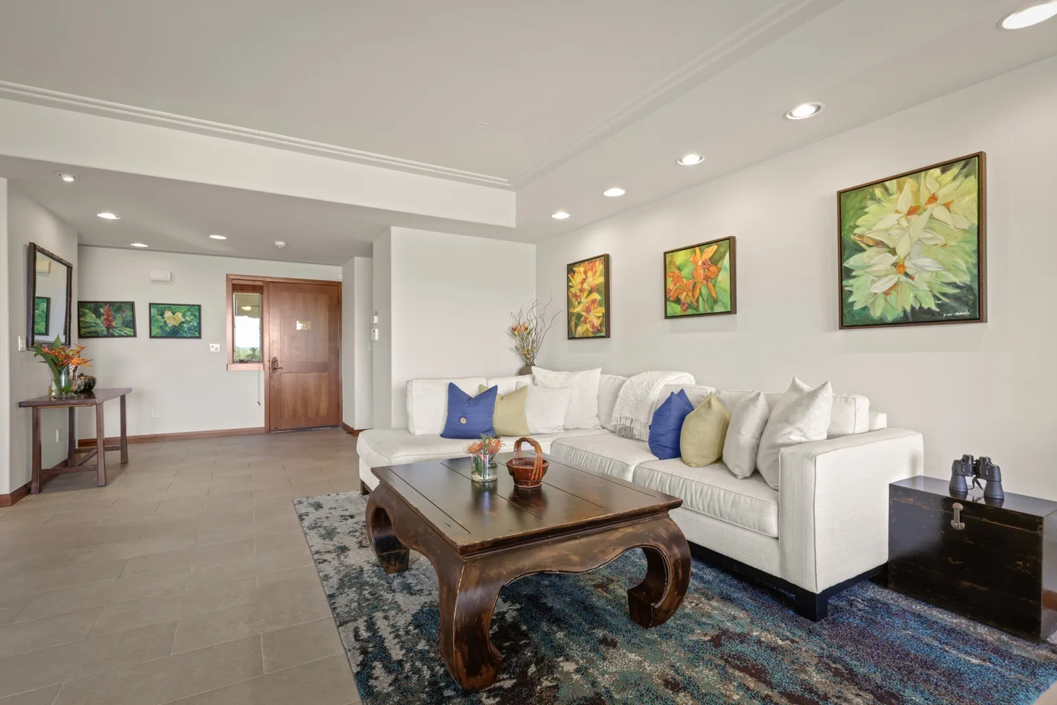 A bright living room with white seating and framed artwork.