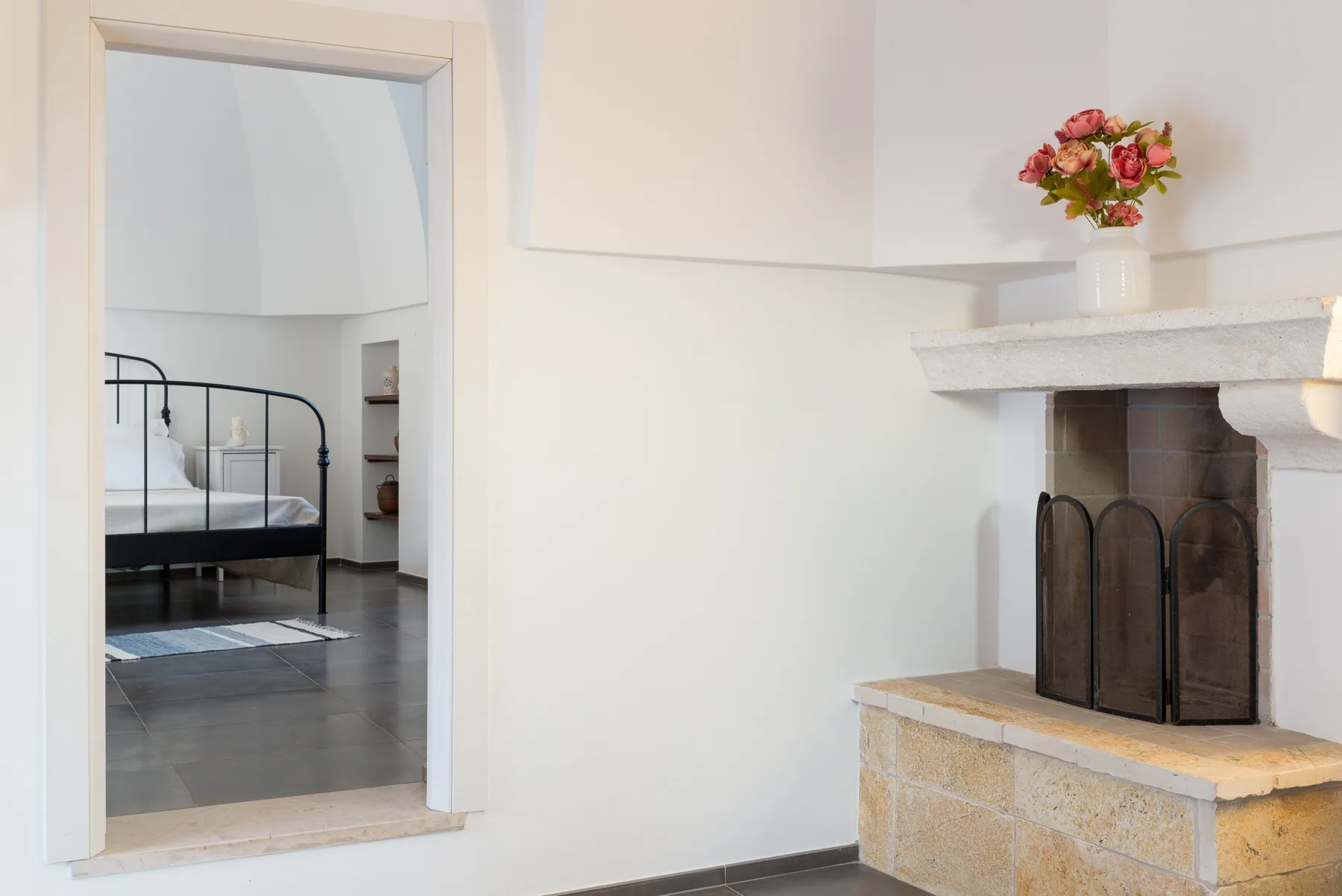 Se ve un dormitorio a través de una puerta abierta junto a una chimenea con flores.