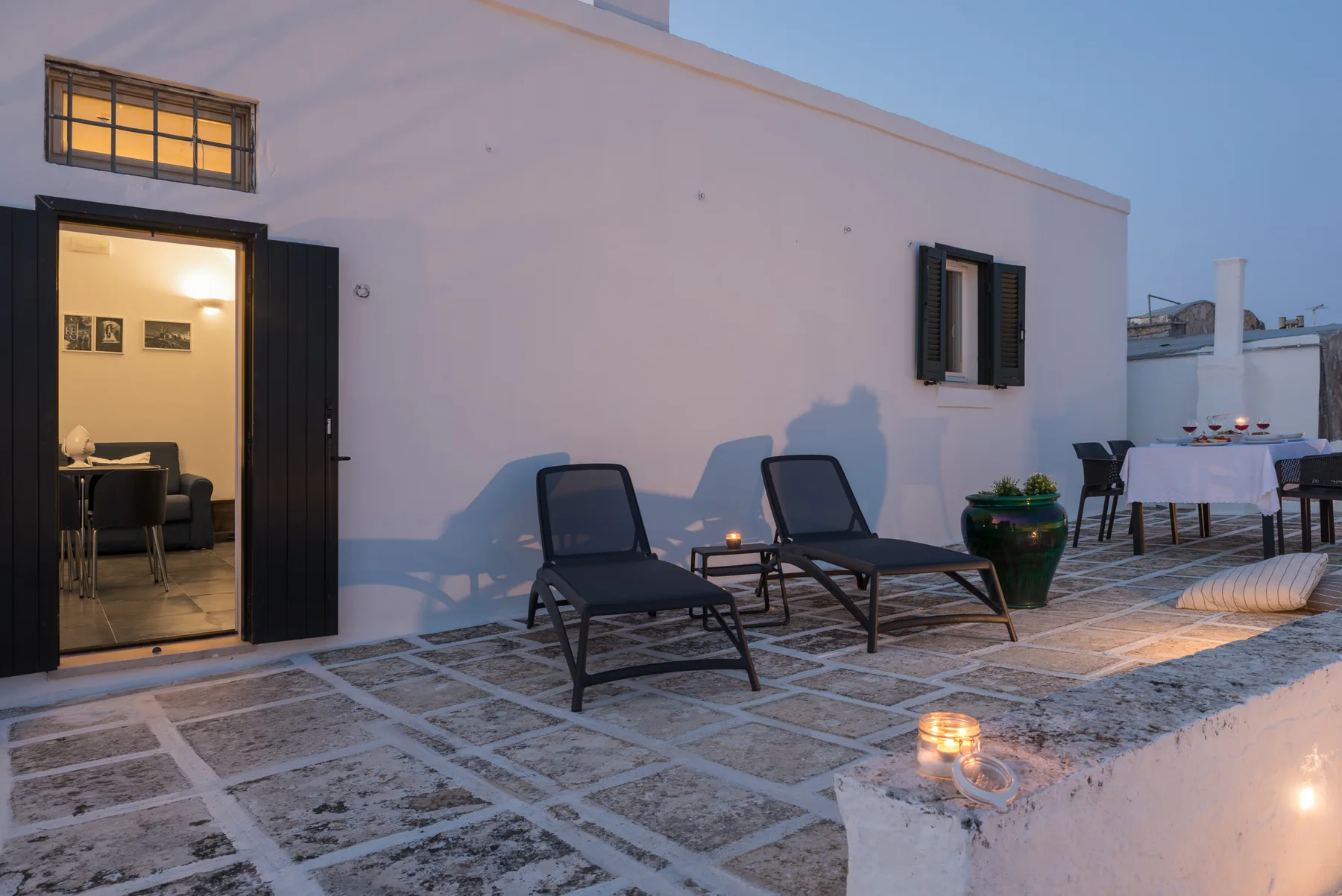 Una terraza en la azotea con asientos, una planta en maceta y una mesa de comedor.