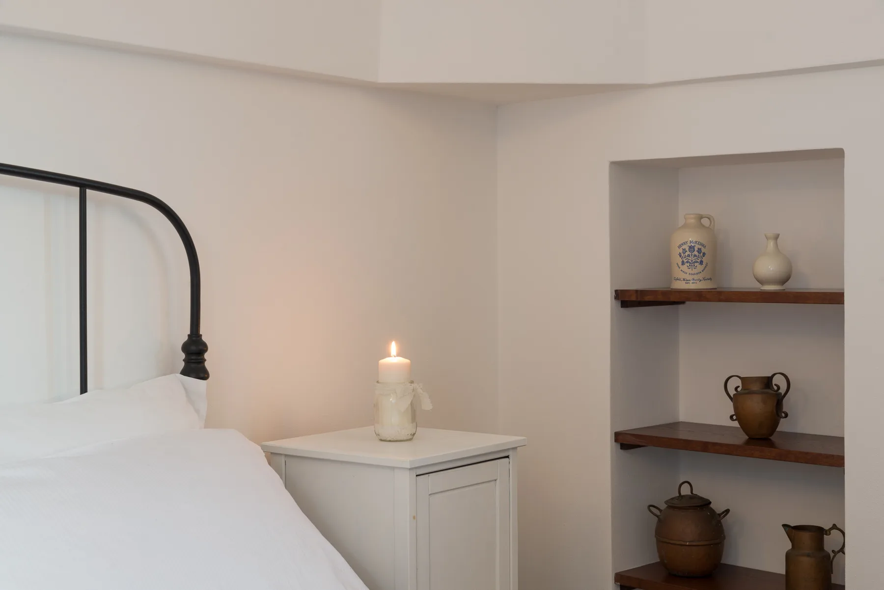 Un dormitorio con una cama, una mesita de noche y una vela encendida.