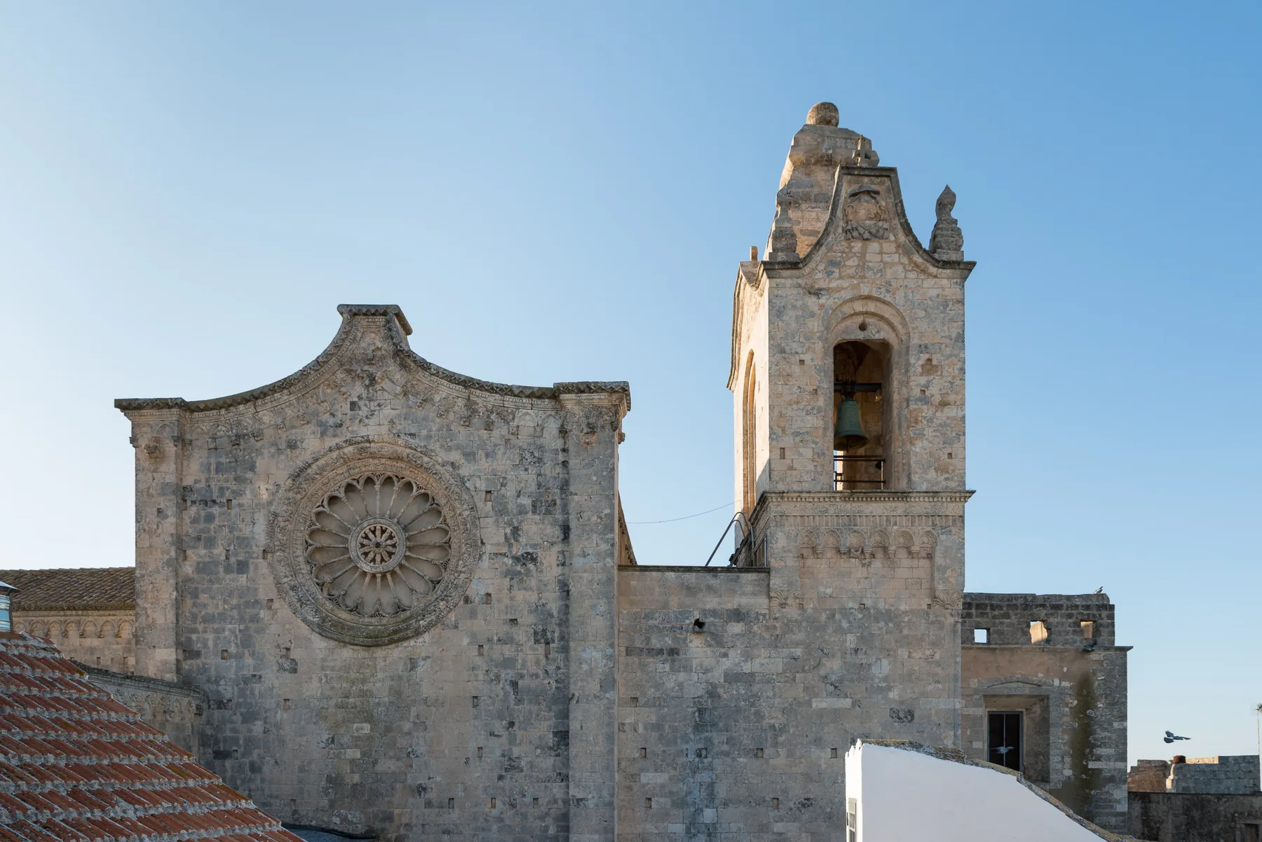 Fachada de una iglesia histórica de piedra con rosetón circular y campanario.