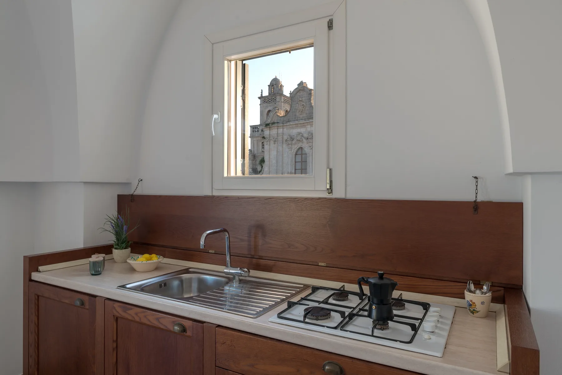 Una encimera de cocina con fregadero y cocina de gas bajo una ventana.