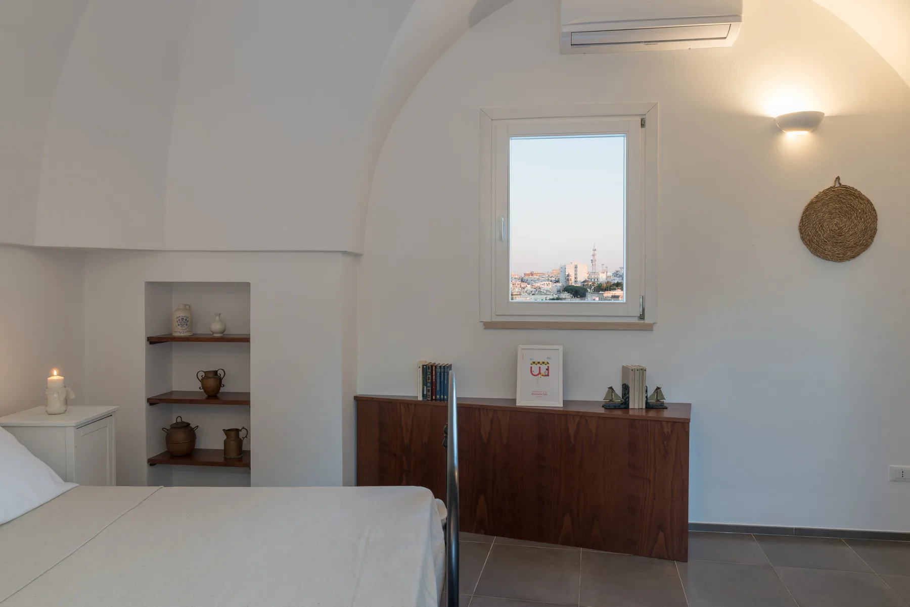 Un dormitorio con una cama y una cómoda de madera bajo una ventana.