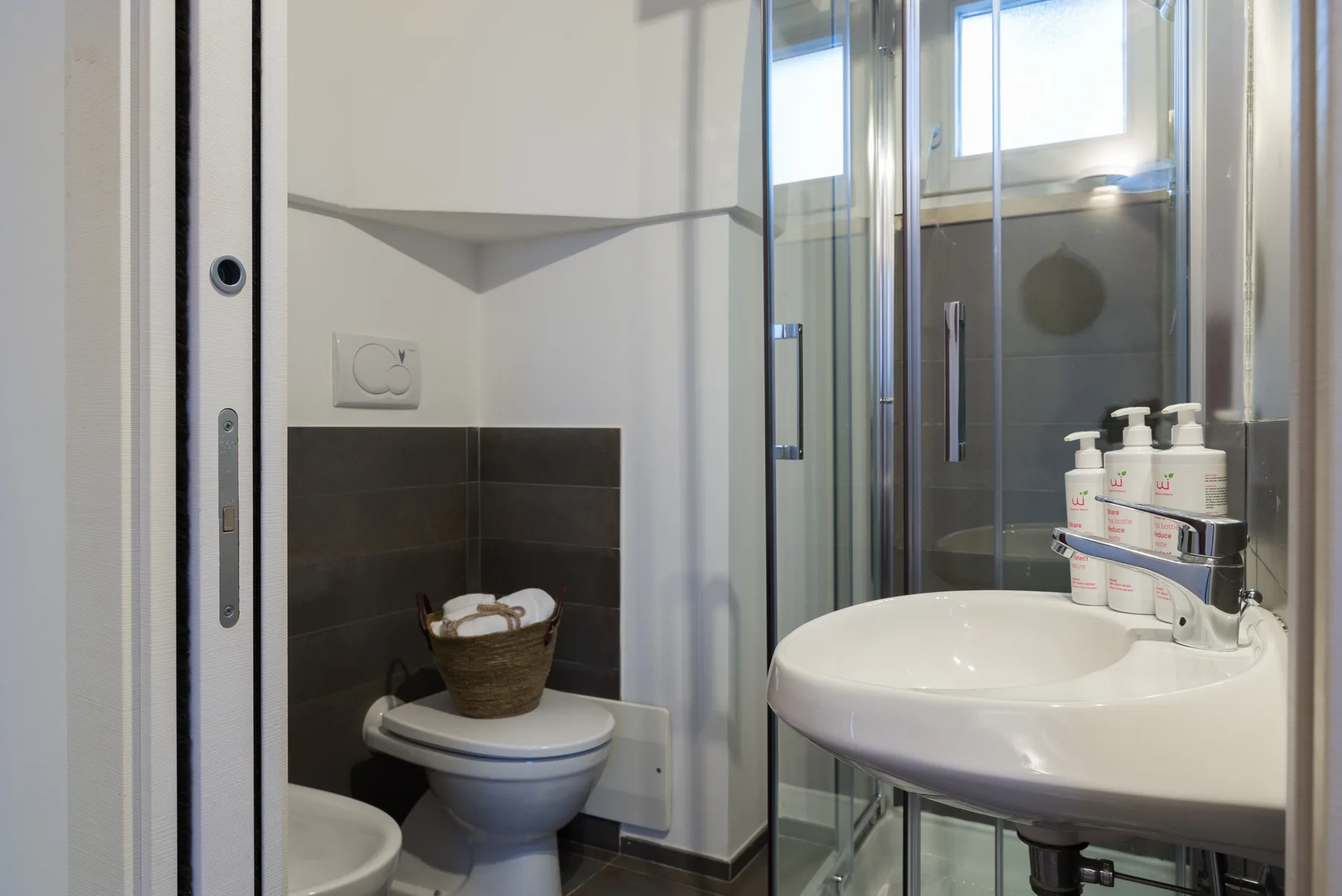 Un baño con lavabo, inodoro y ducha con mampara de vidrio.