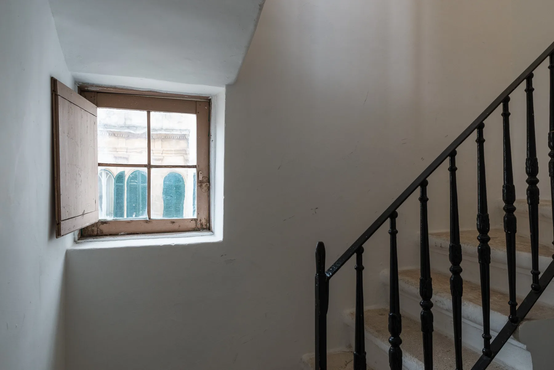 Una escalera con una ventana pequeña y una barandilla oscura.