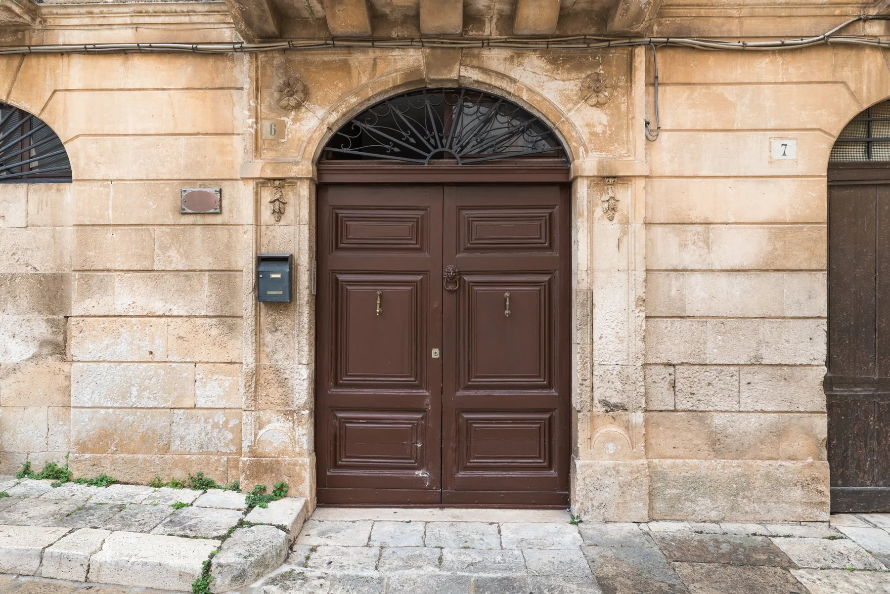 Una puerta doble de madera oscura en la fachada de un edificio de piedra.
