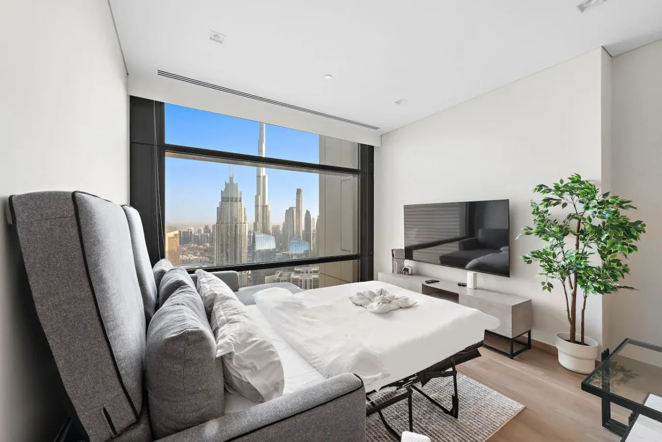 Un dormitorio luminoso con una cama junto a un gran ventanal con vistas a la ciudad.