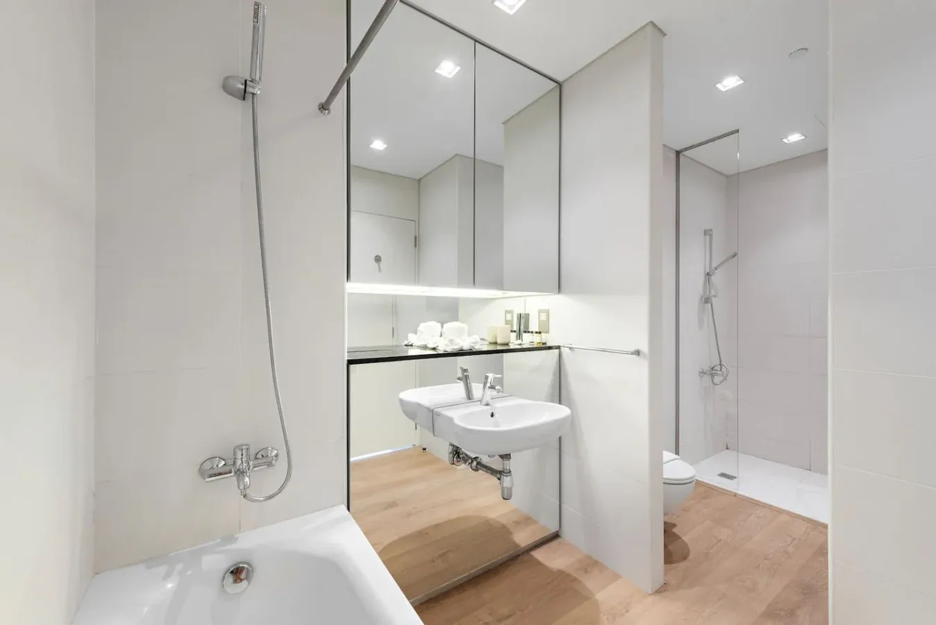 Un baño luminoso con bañera, lavabo suspendido y ducha acristalada.