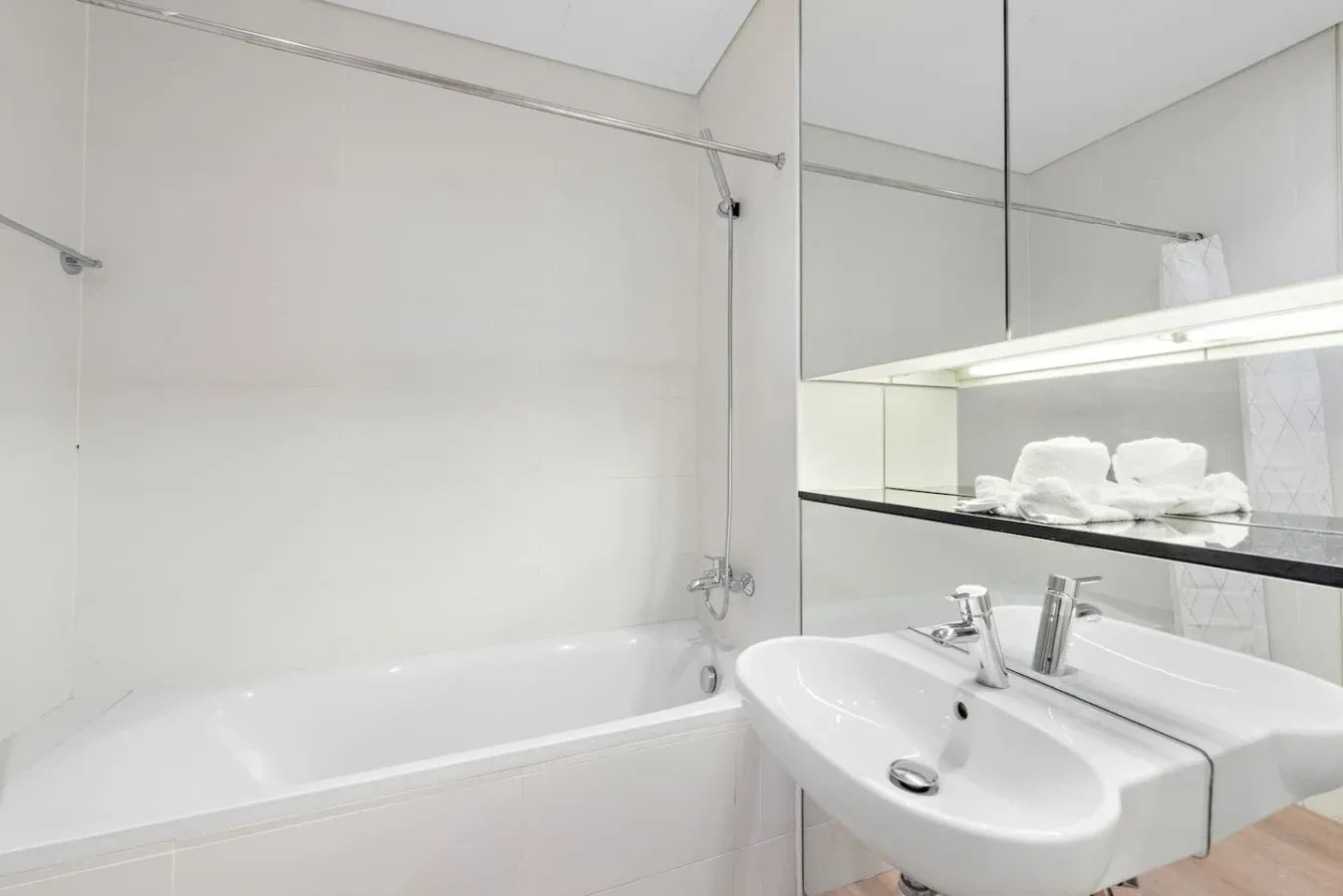 Un baño luminoso con bañera, lavabos y espejo.