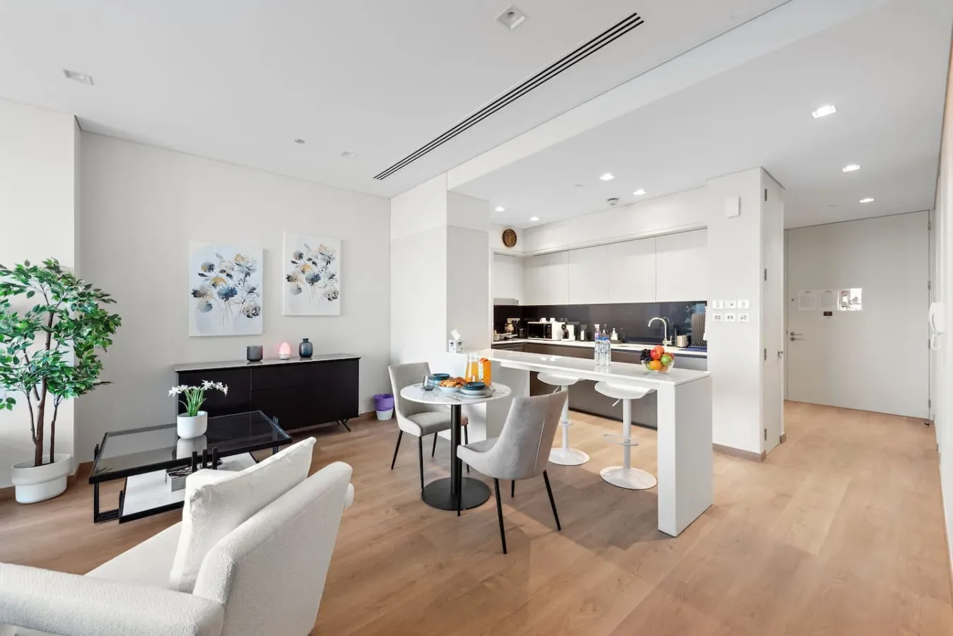 Una luminosa sala-comedor de concepto abierto con cocina y piso de madera clara.