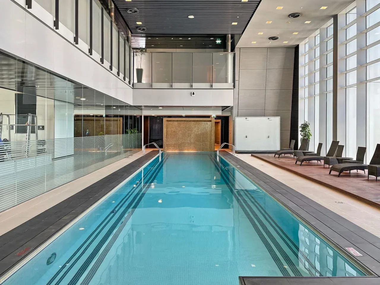 Una piscina cubierta con asientos junto a grandes ventanales.