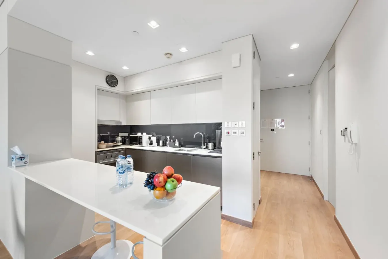 Una cocina luminosa con una isla blanca y un frutero sobre la encimera.