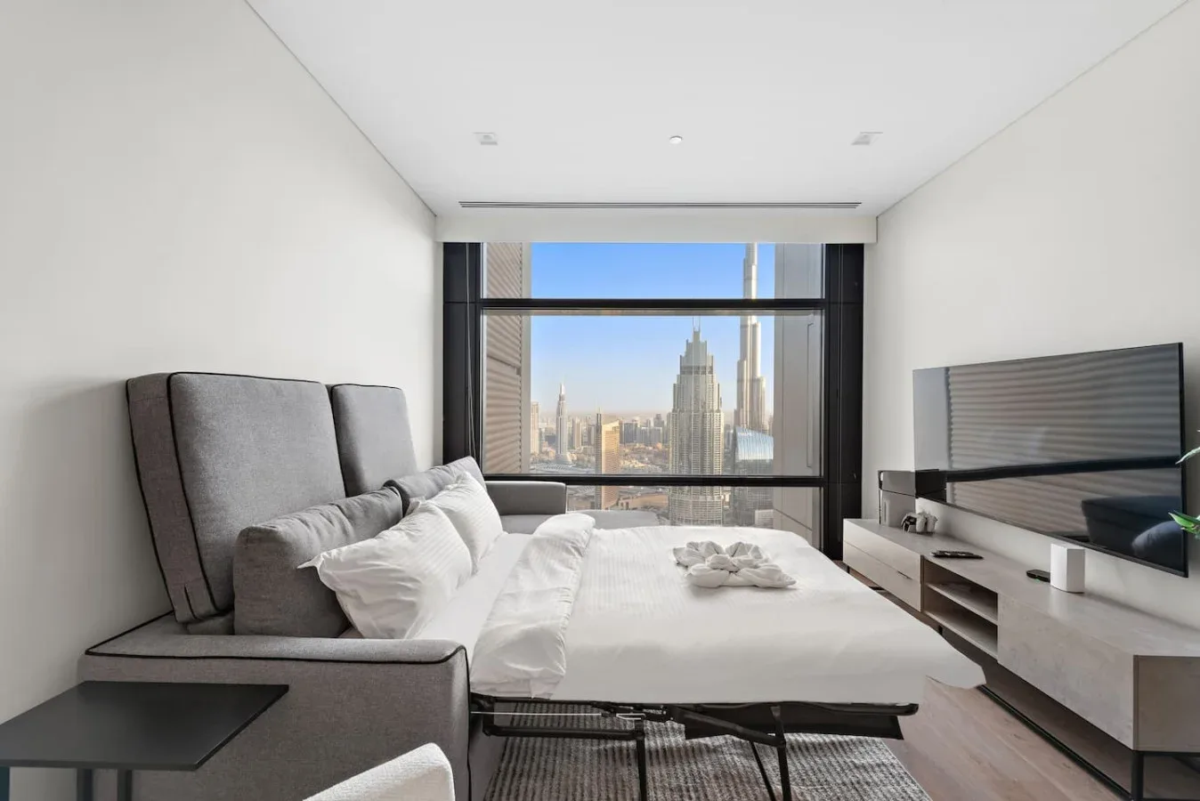 Un dormitorio luminoso con una cama grande y vistas de la ciudad por la ventana.