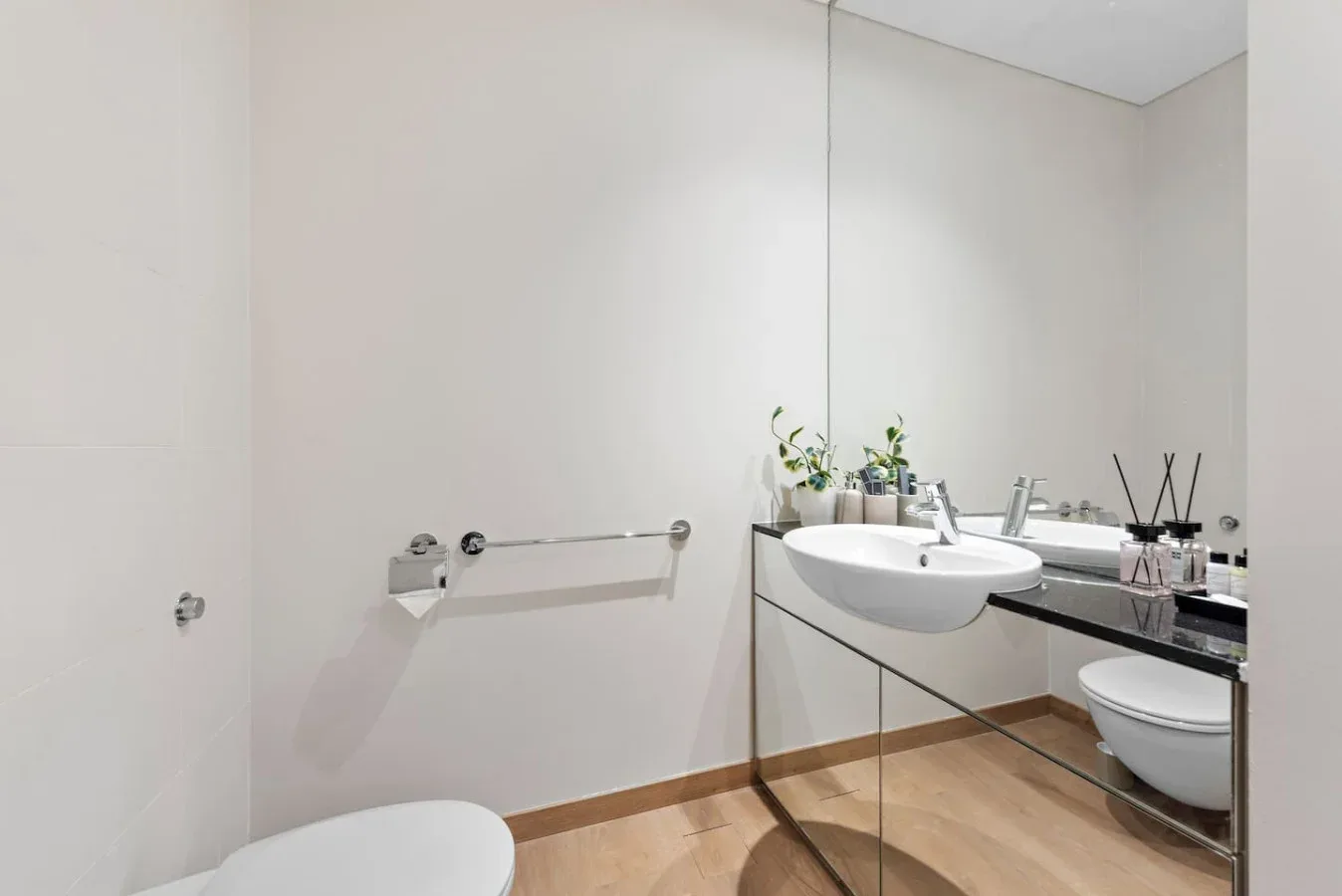 Un baño moderno con un lavabo de pared y un espejo grande.