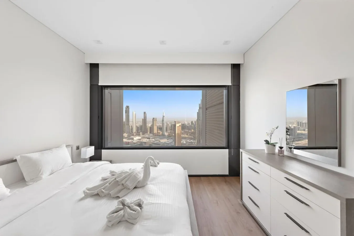 Un dormitorio luminoso con una cama grande y vistas a la ciudad por la ventana.