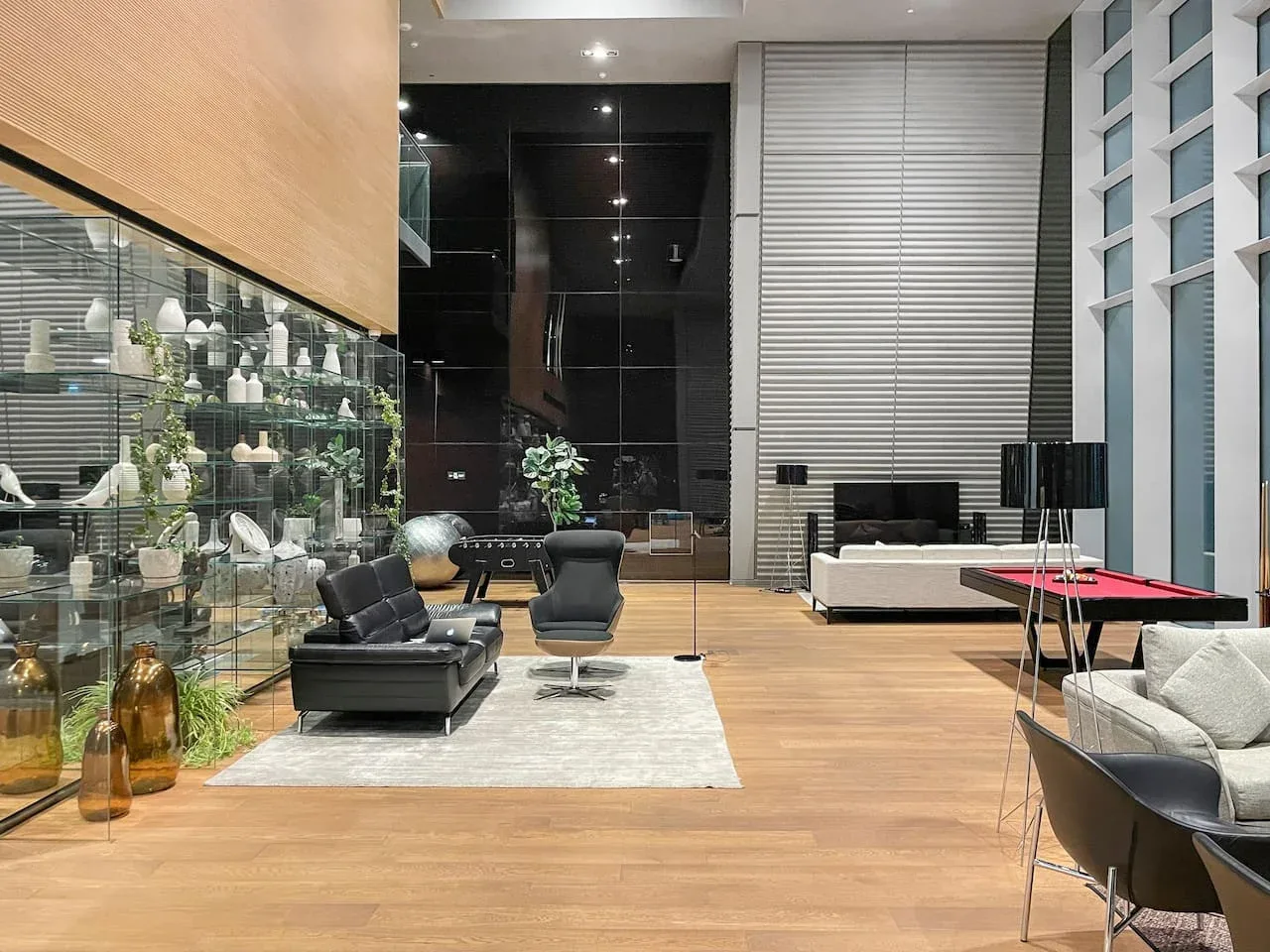 Una sala de estar moderna con asientos, una pared de exhibición de vidrio y piso de madera.