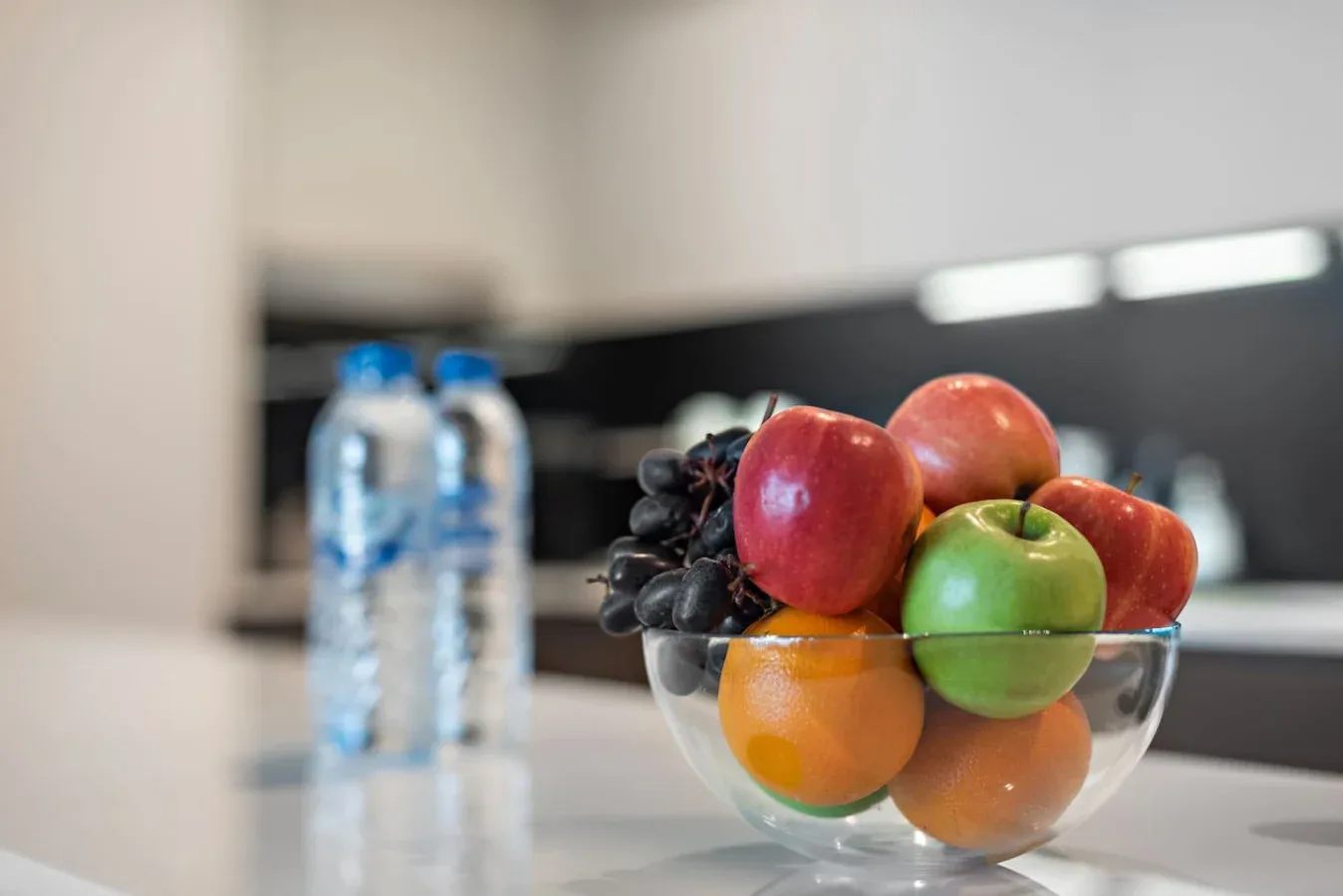 Un frutero con frutas variadas está sobre una encimera de cocina.