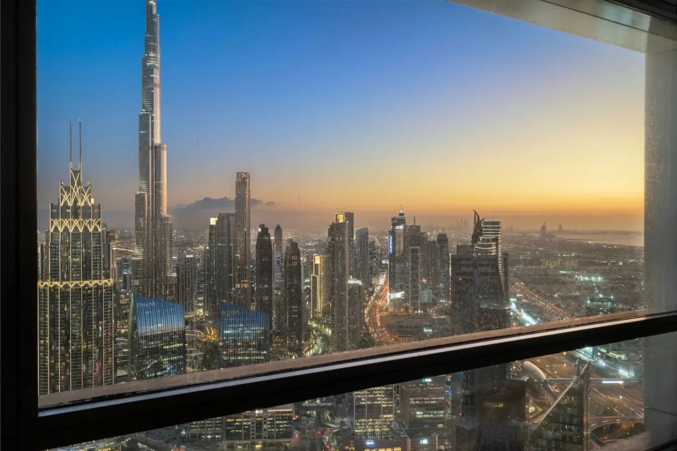 Un horizonte urbano al atardecer se ve a través de una gran ventana.