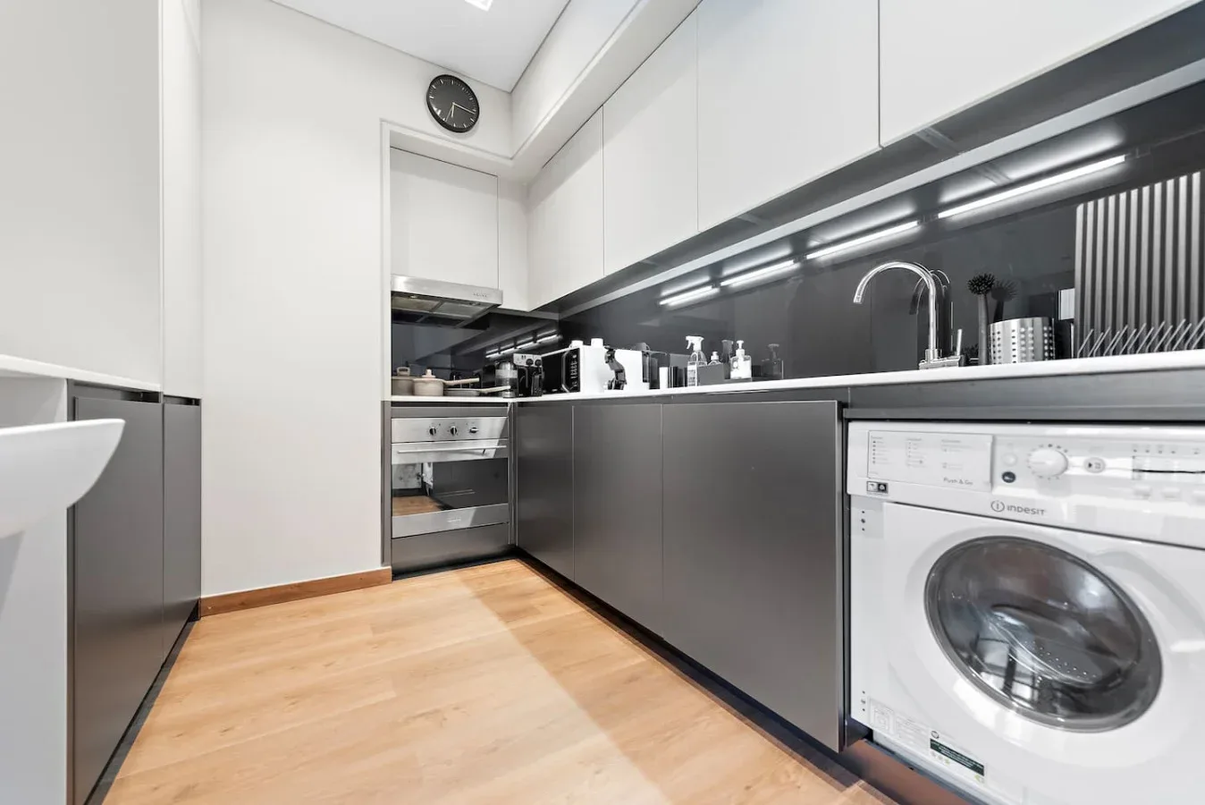 Una cocina moderna con gabinetes oscuros, un fregadero y una lavadora.