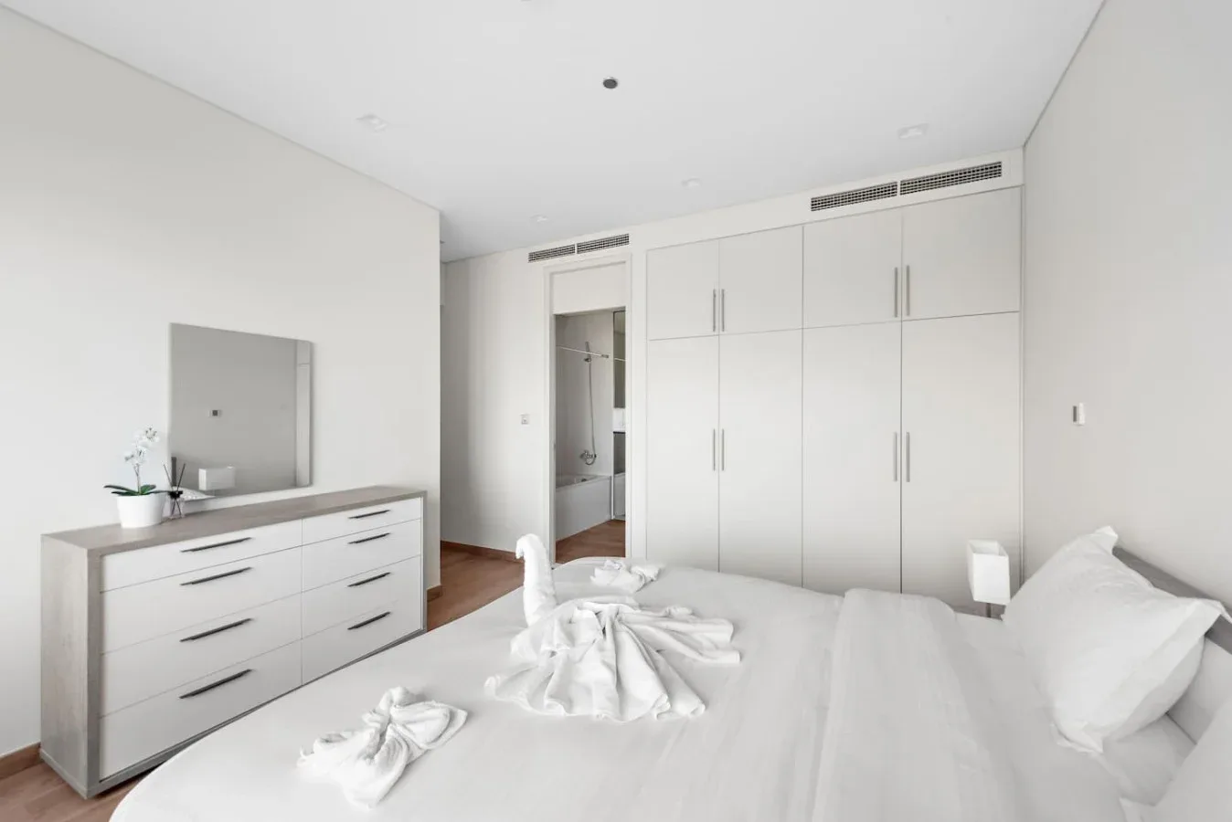 Un dormitorio luminoso con una cama blanca y armarios empotrados.