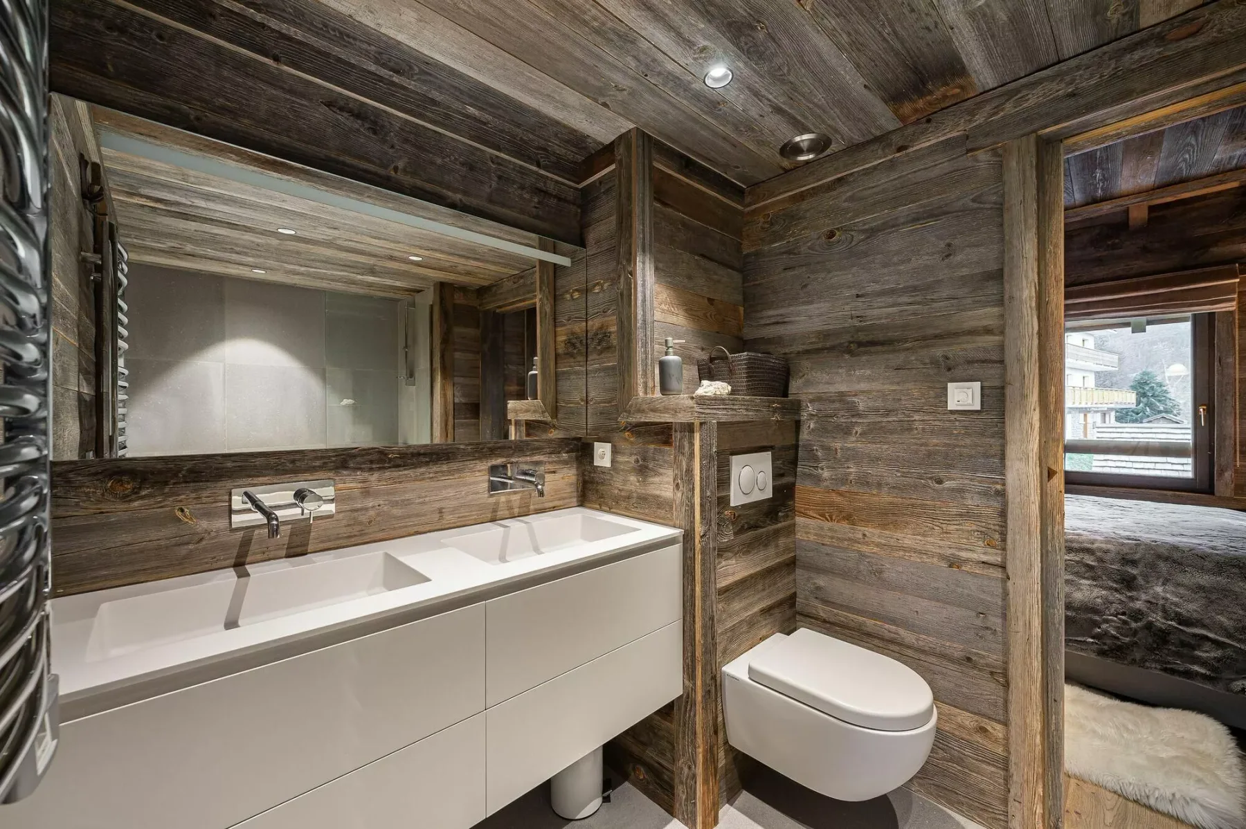 A wood-paneled bathroom with a wide vanity, mirror, and toilet.