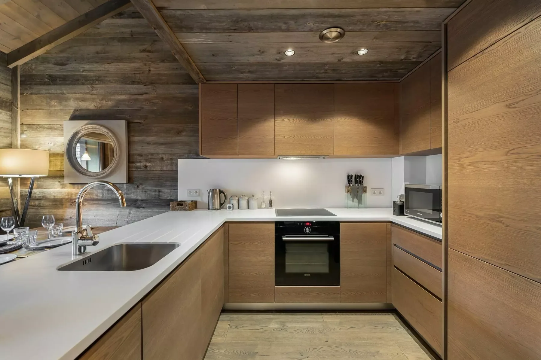 A modern kitchen with wood cabinetry, white countertops, and a built-in oven.