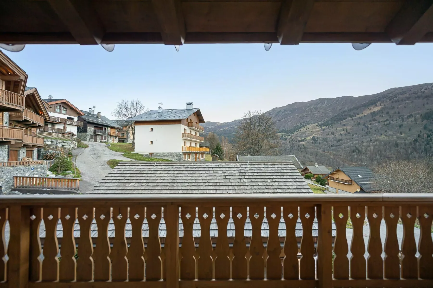 A balcony overlooks chalet-style buildings and a mountain slope.