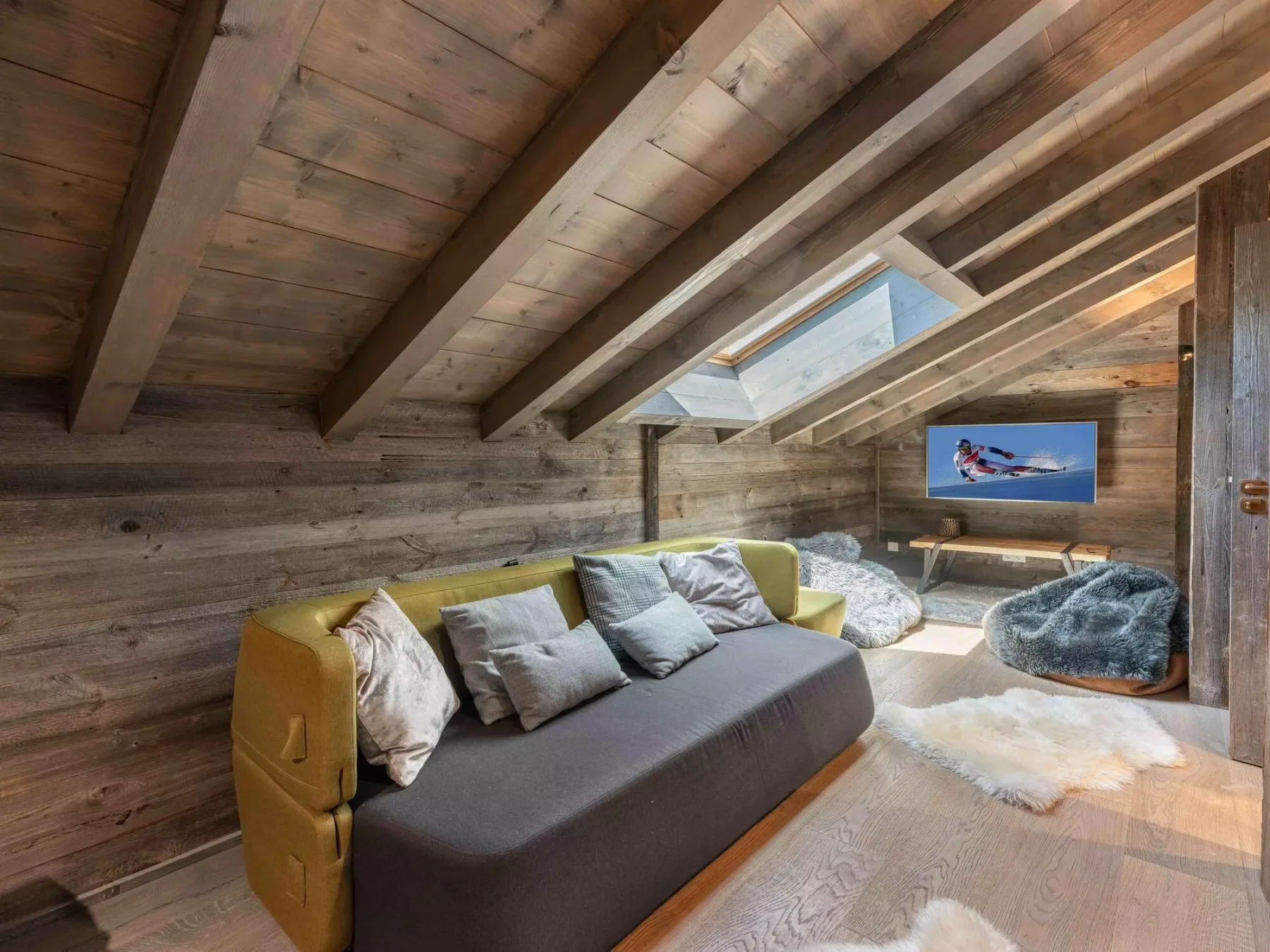 A wood-paneled room with a sofa, skylight, and television.