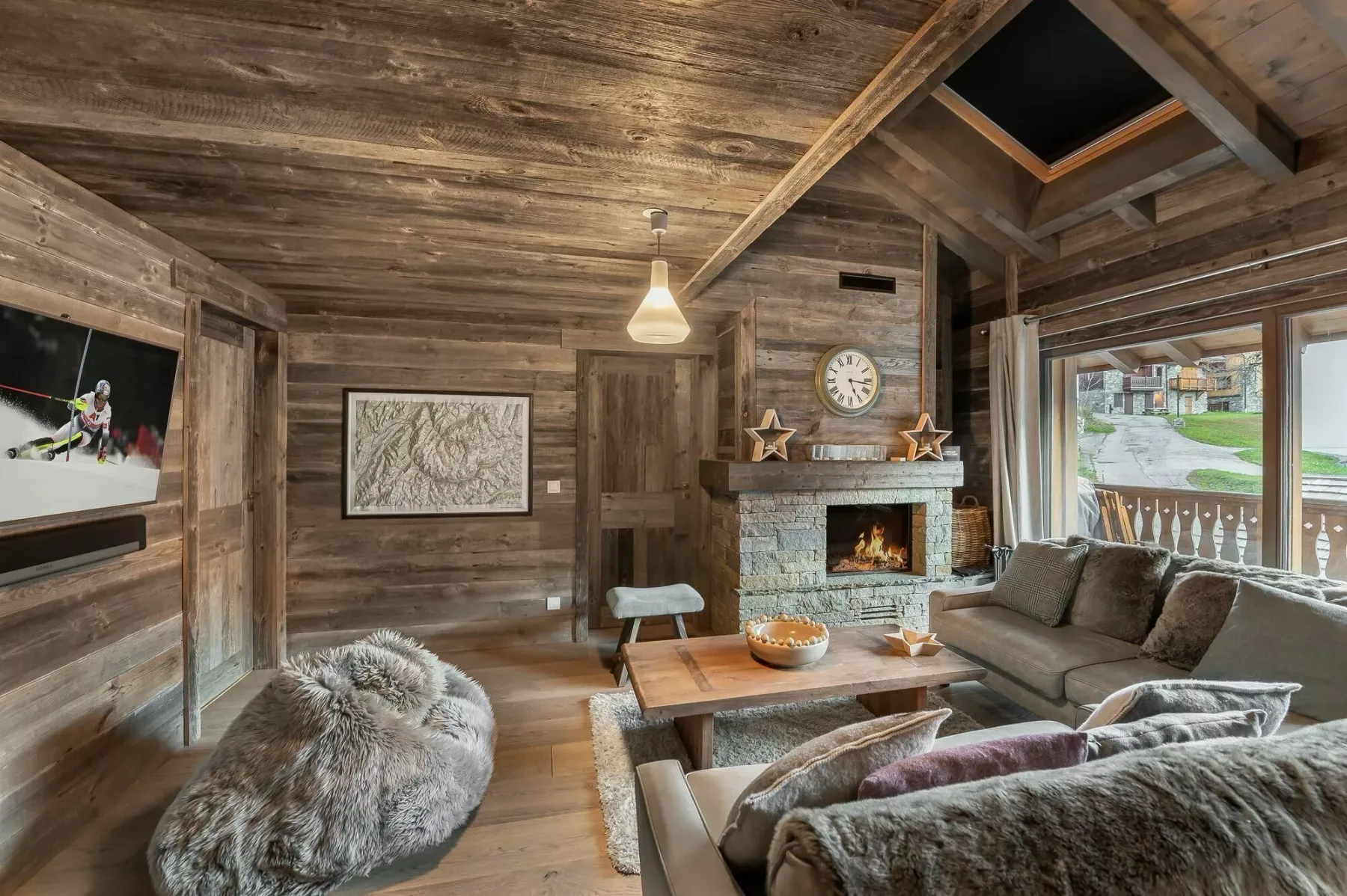 A wood-paneled living room with seating around a coffee table and fireplace.